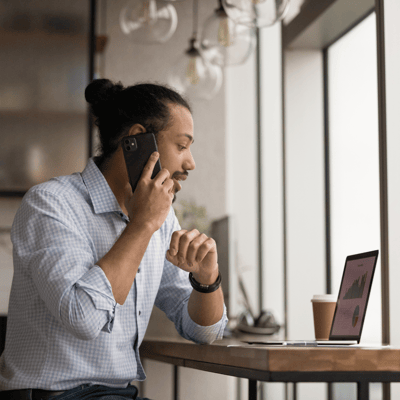 Small business owner on the phone while reviewing banking metrics on his computer