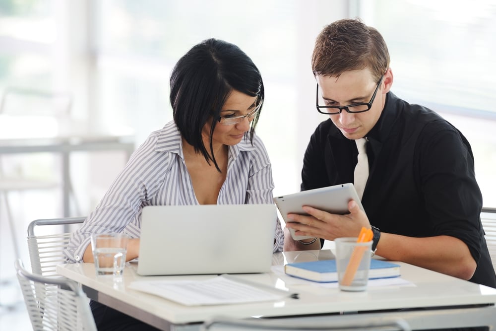 Three business people working at office with paperwork using tablet and laptop