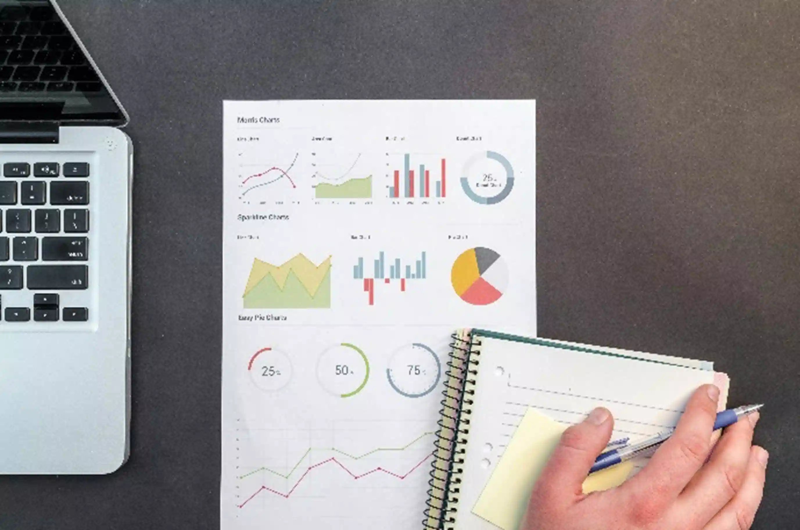 Main d'un homme d'affaires avec un ordinateur portable et un papier montrant des graphiques et un cahier