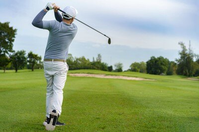 Golf player swinging its gold club to hit the ball
