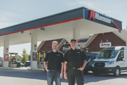 Deux employés de Harnois Énergies se tiennent devant une station-service