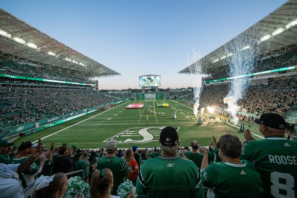 Les Roughriders de la Saskatchewan applaudissent dans les tribunes alors que des feux d'artifice sont tirés dans l'arène.