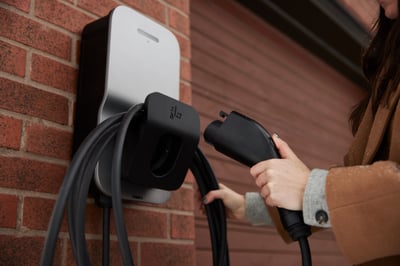 Une personne s'empare d'un chargeur de véhicule électrique FLO à domicile