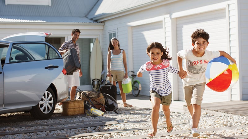 Kids running to beach to play while parents unpack rental car.