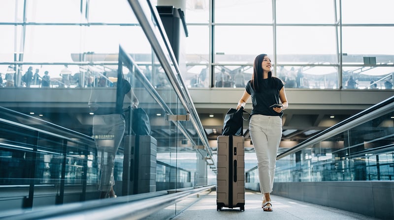 Une femme marche sur un tapis roulant à l'aéroport avec ses bagages.