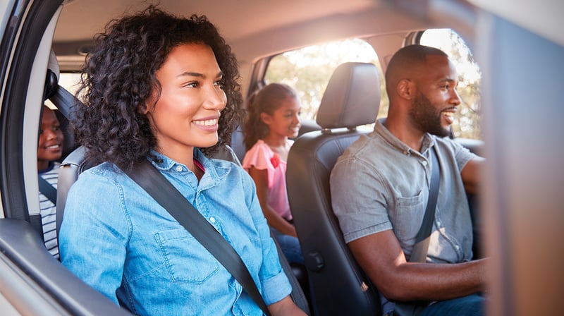 Family of four happily driving in rental vehicle.