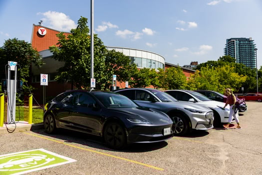 Une femme se dirige vers son véhicule électrique en charge.