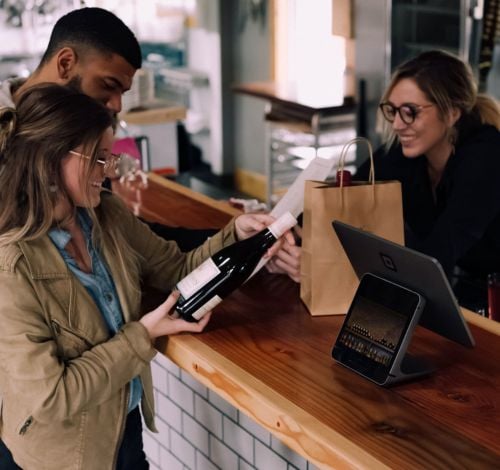 Two customers checking a wine bottle at a small business store