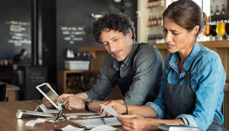 Deux propriétaires de petites entreprises en train de vérifier leurs coûts, factures et reçus