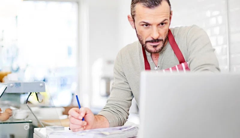 Small business owner writing his costs on a notepad