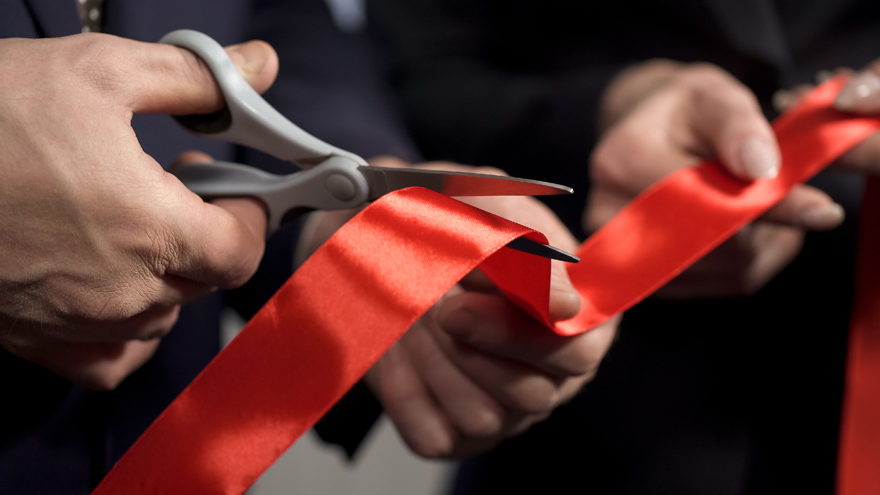 Red ribbon being cut with scissors