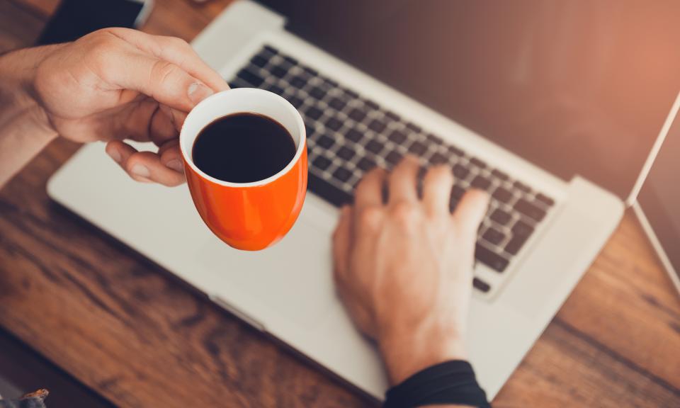 Person holding coffee mug while on the computer