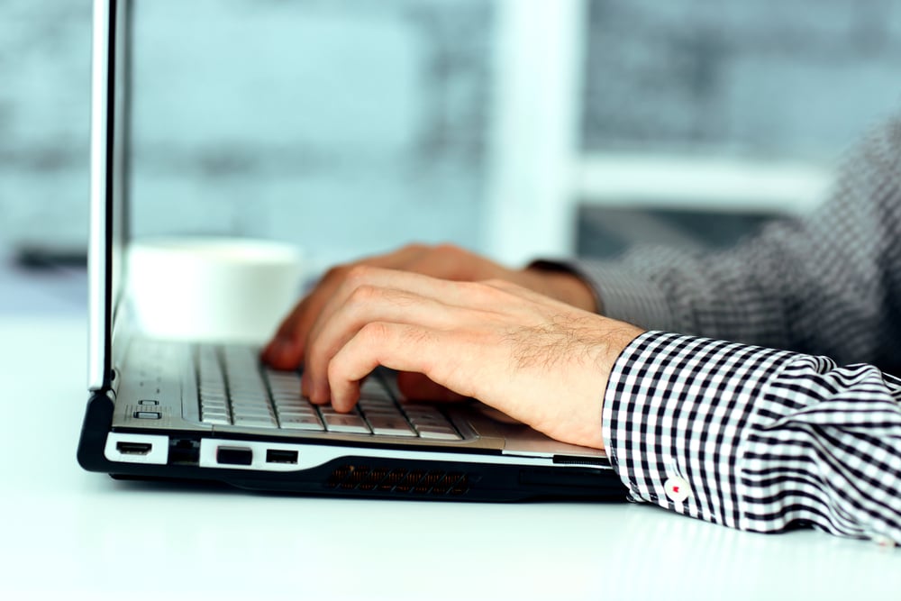 Closeup image of a male hands typing on laptop keyboard