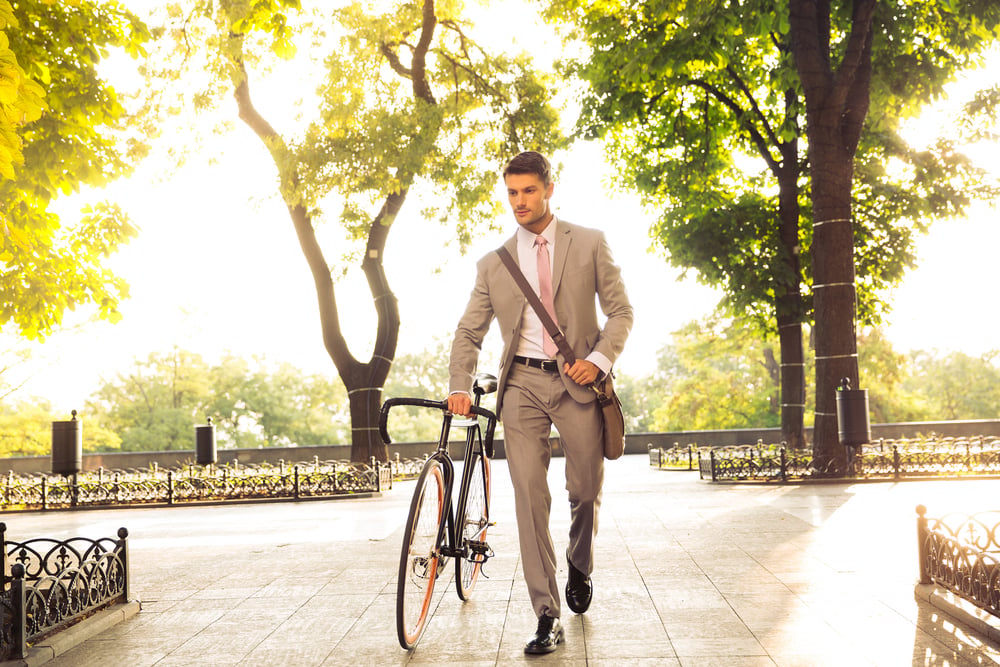 Employee outdoors walking his bike