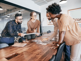a diverse team of two women and two men collaborating on a project in a boardroom.