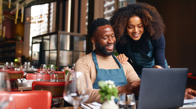 Small business owners smiling at computer screen