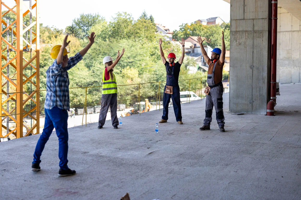 4 construction workers stretching before starting work