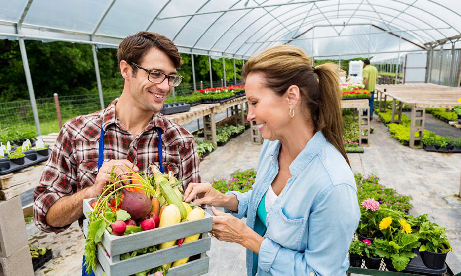 Customer and farmer looking at box of produce