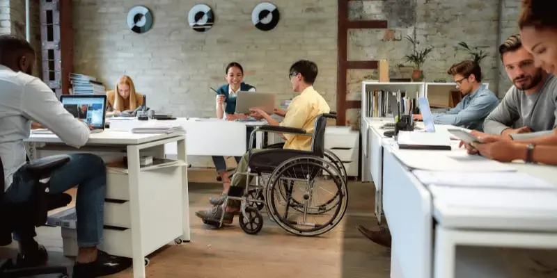 Employee in wheelchair collaborating with other employees
