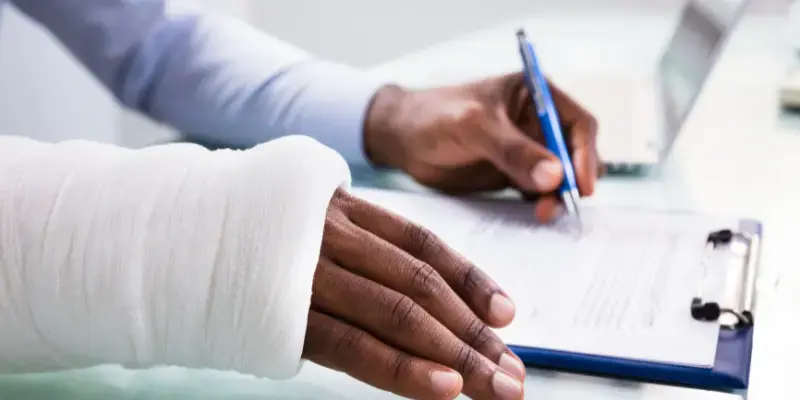personne avec un bras cassé signant un document