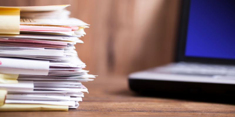 Stacks of paperwork in front of a laptop