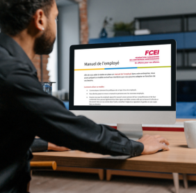 Image d’un homme assis devant un ordinateur de bureau avec le modèle de manuel de l’employé de la FCEI ouvert sur son écran.