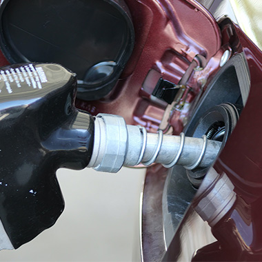 Gas hose going into gas tank of burgundy car