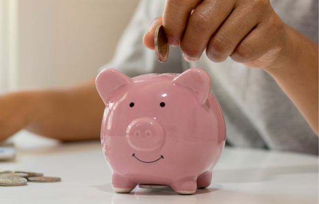 Person putting coin in piggy bank