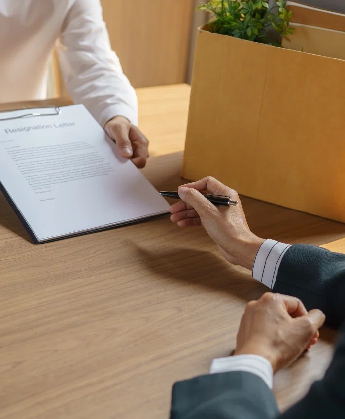 A small business owner is handing the notice and severance pay documents to one of his employees