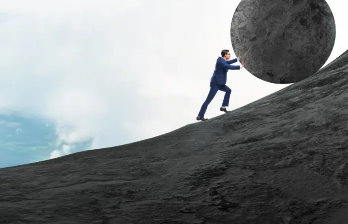 A small business owner pushing a large stone on a mountain symbolizing the weight of payroll tax on SMEs in Canada