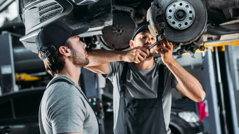 two employees working on a car in an automotive shop