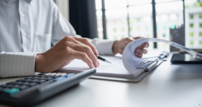 Man calculating numbers and reviewing paperwork to represent the budget