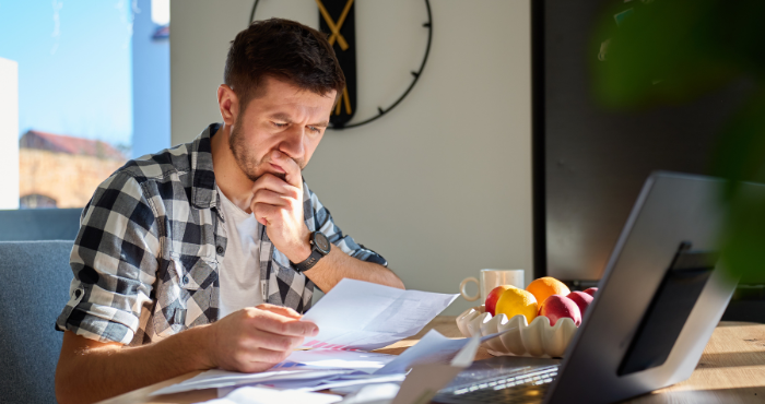 Business owner working at a table reviewing documents in front of a laptop