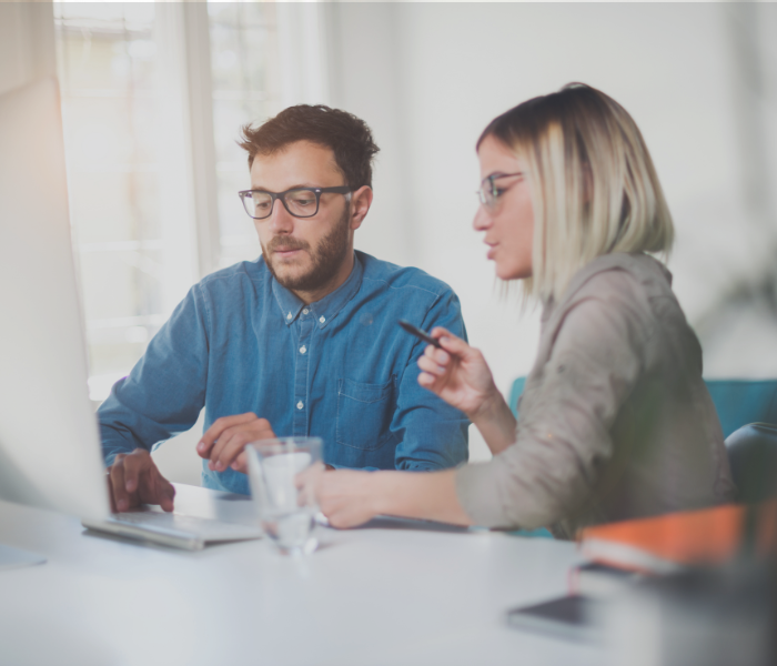 two employees at a computer representing a discussion around provincial budgets
