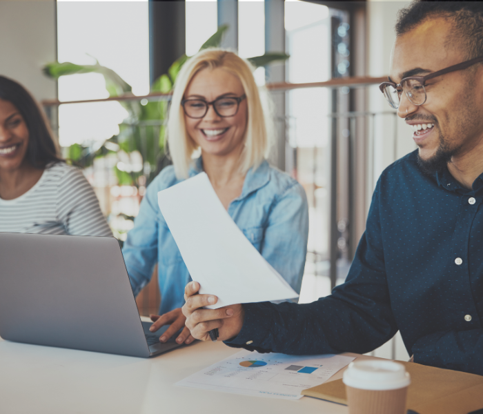 group of happy people looking at a computer and paperwork at a desk representing small business tax wins