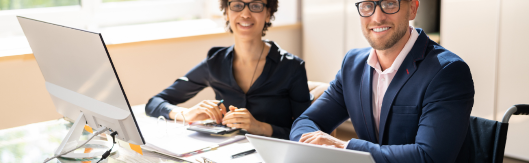 two people in business attire working at a desk representing doing taxes and budget review
