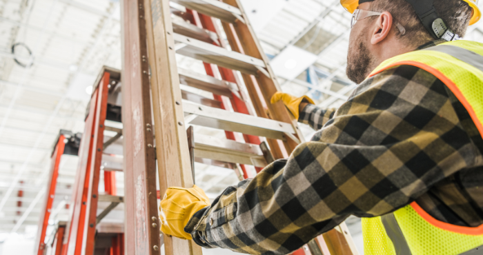 Worker in safety gear setting up a ladder