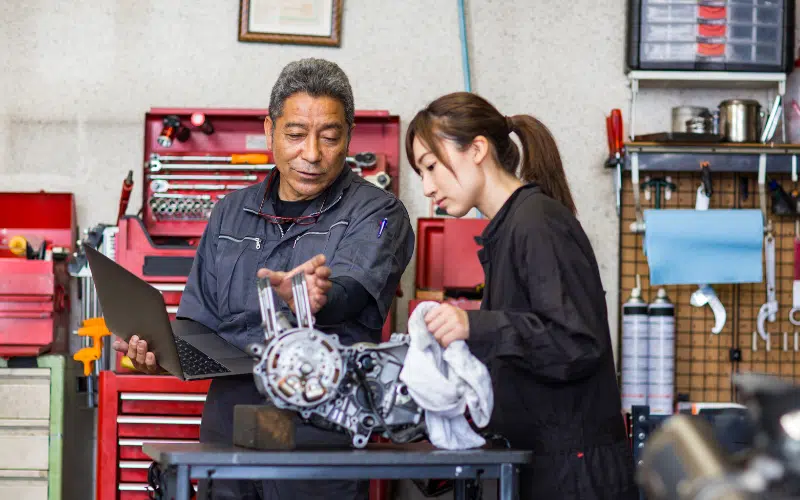 Deux propriétaires de petite entreprise en train de travailler sur une machine dans leur atelier