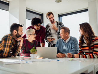 Employees gathered around laptop chatting