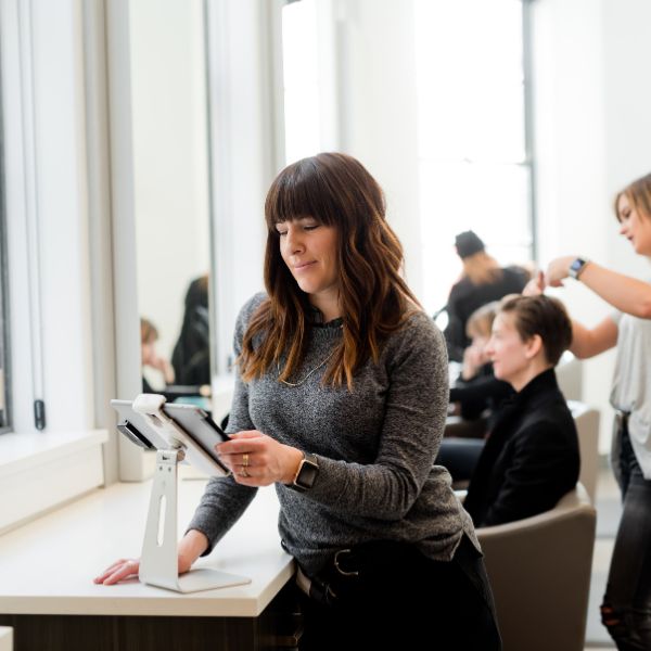 Propriétaire de petite entreprise dans son salon de coiffure en train de regarder sa tablette