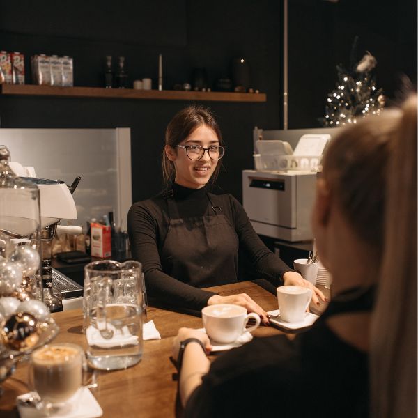 A small business owner serving cups of coffee to her costumer