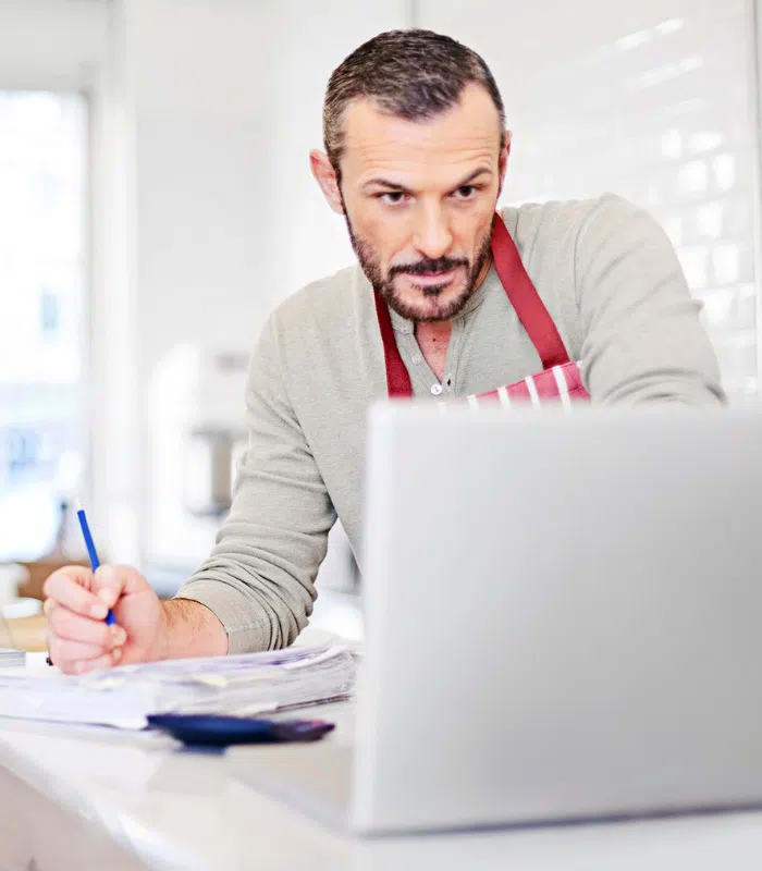 Small business owner writing his business costs on a notepad