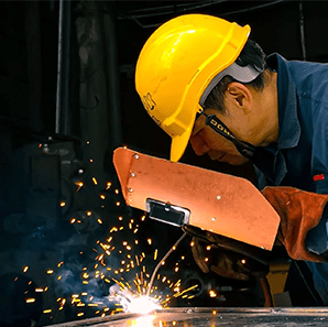 Image of worker covering face with mask while welding